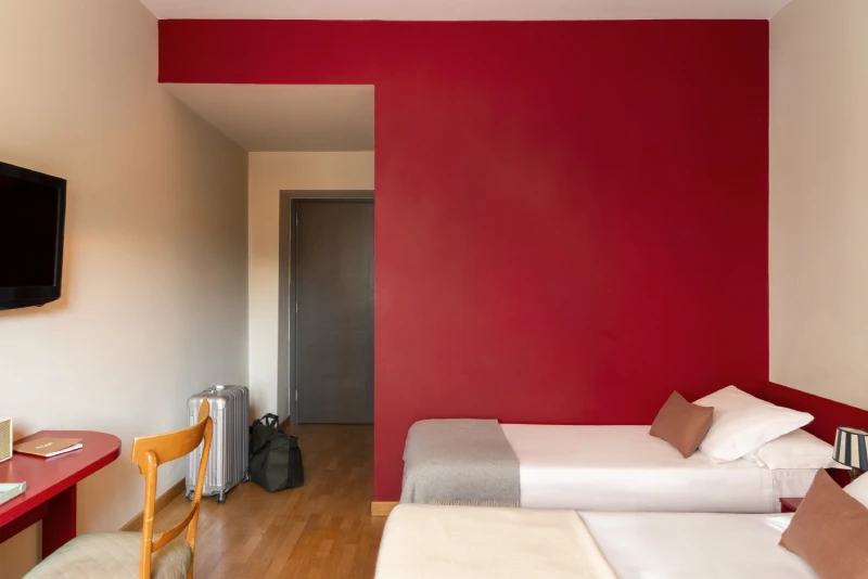 Triple room with single beds, red wall and minimalist furnishings, cozy atmosphere in Monti district Rome - Monti First, BZAR hotels in Rome